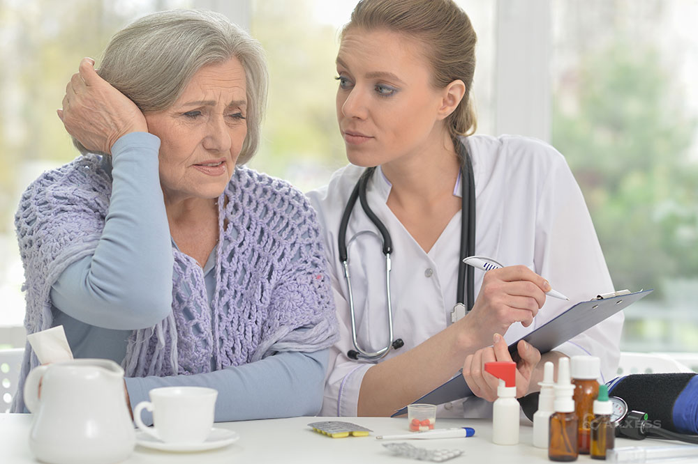 A female clinicians holds a clipboard and speaks to an elderly female expressing confusion