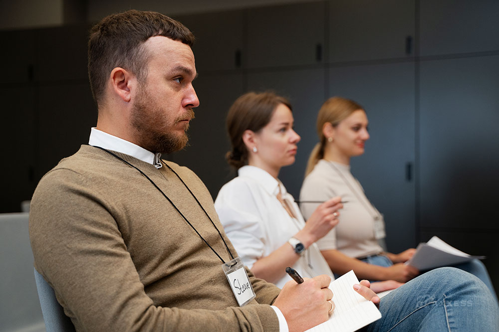 Three business professionals sit watching a presentation.