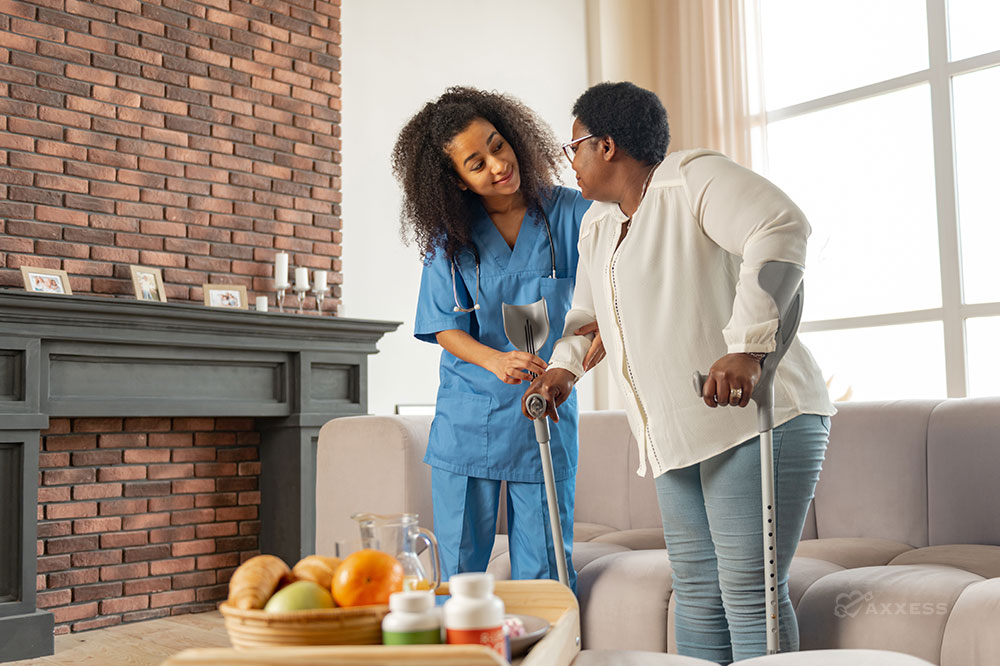 A female clinician assists a woman using canes in her home