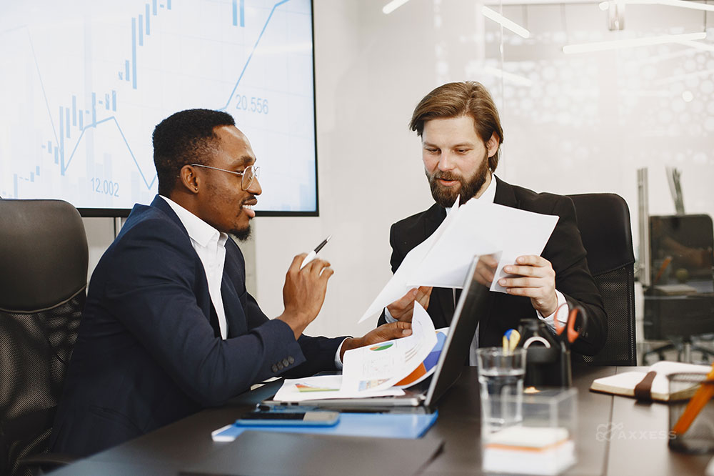 Two financial leaders sit together at a table looking over documents