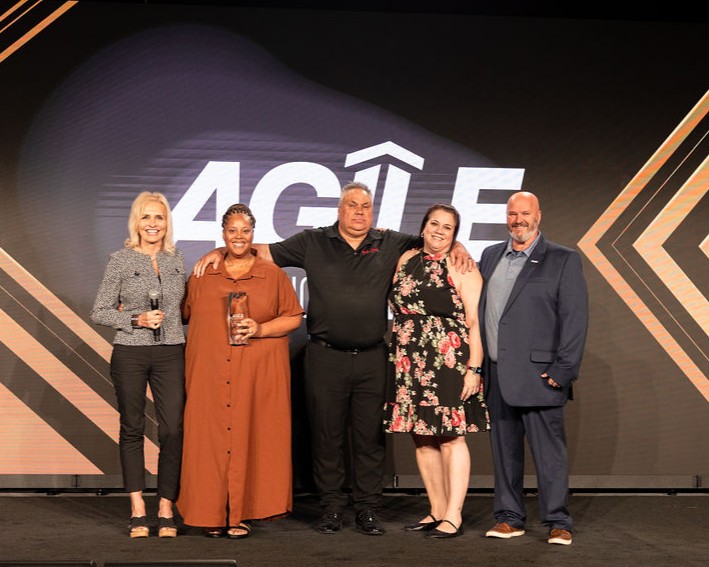 Healthcare leaders and award recipients stand together on the AGILE conference stage in Dallas, celebrating innovation and leadership in care at home during a national home health and hospice industry event.