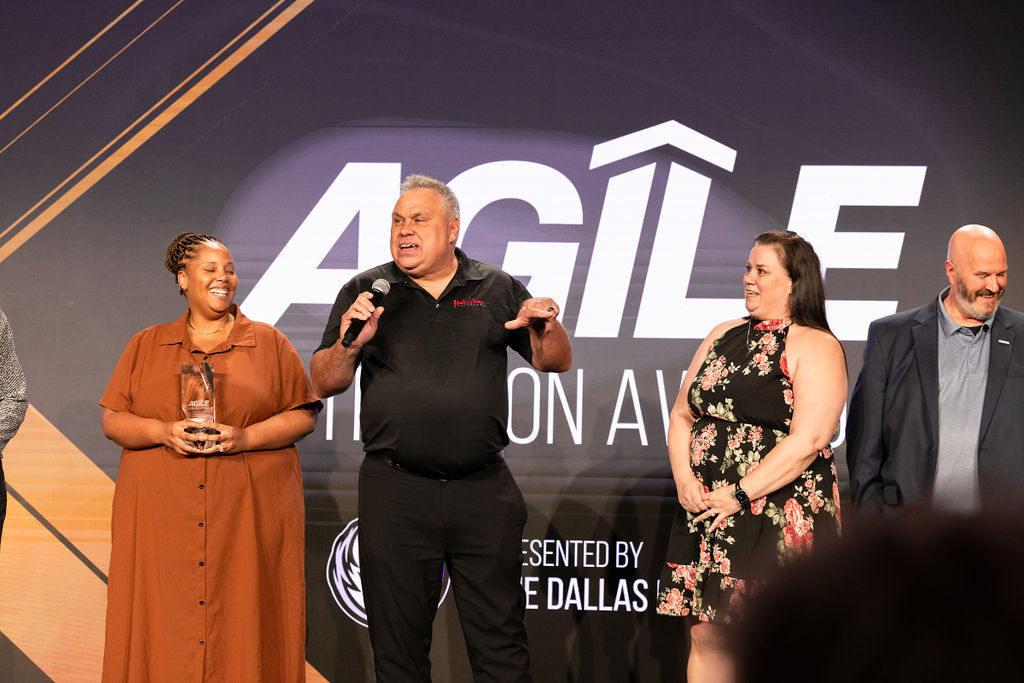 A healthcare executive speaks on stage at the AGILE conference in Dallas as award recipients from home health and hospice organizations are recognized for excellence, innovation, and impact in care at home.